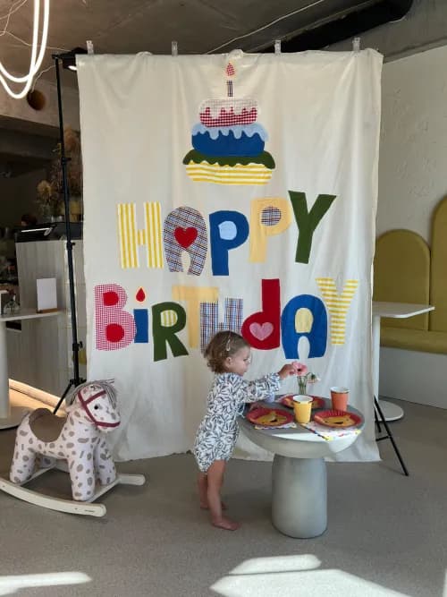 Dziecko przy urodzinowym stole na tle kolorowej dekoracji Happy Birthday